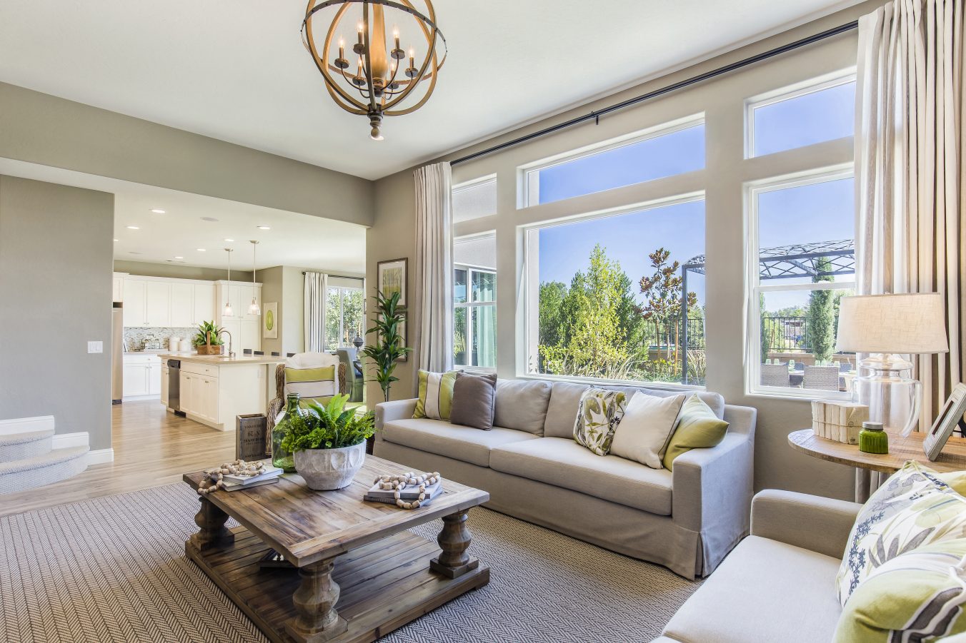 Sunlight shining into large living room with view of kitchen and backyard