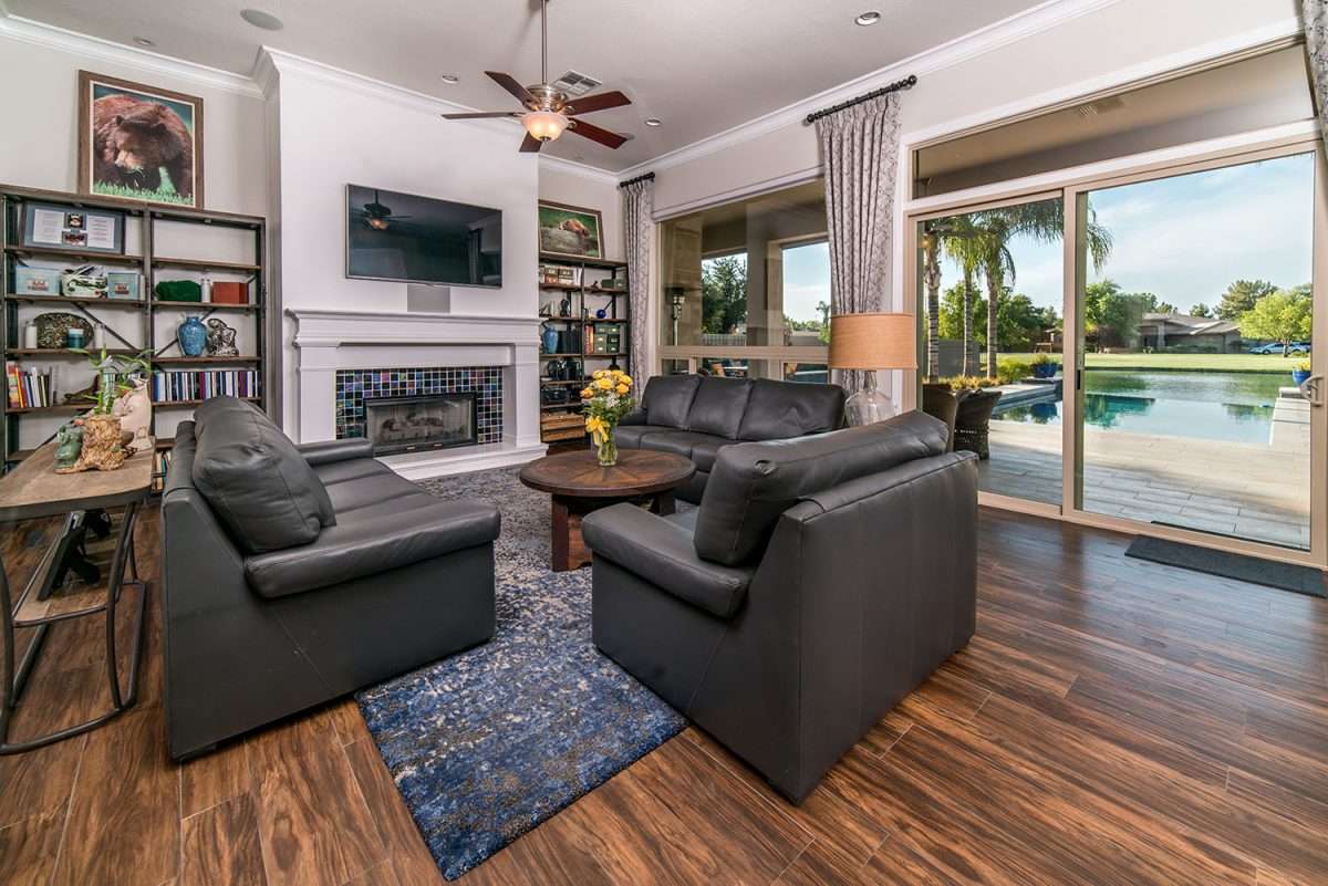 Living room with comfy leather couches and a wall of sliding doors overlooking a swimming pool